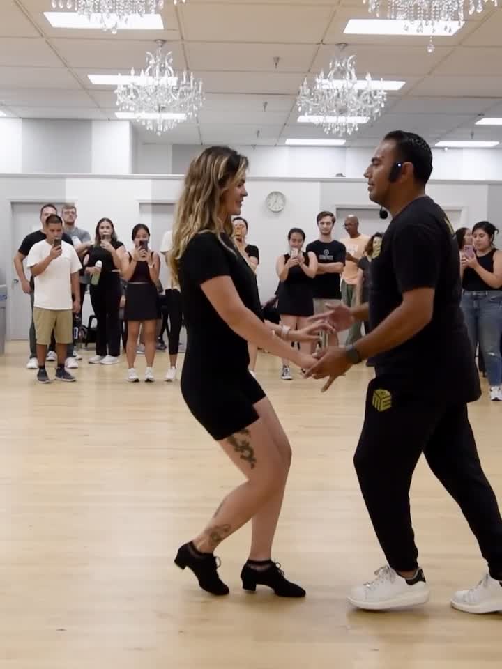 A couple dancing Salsa On2 in a Melómano group class