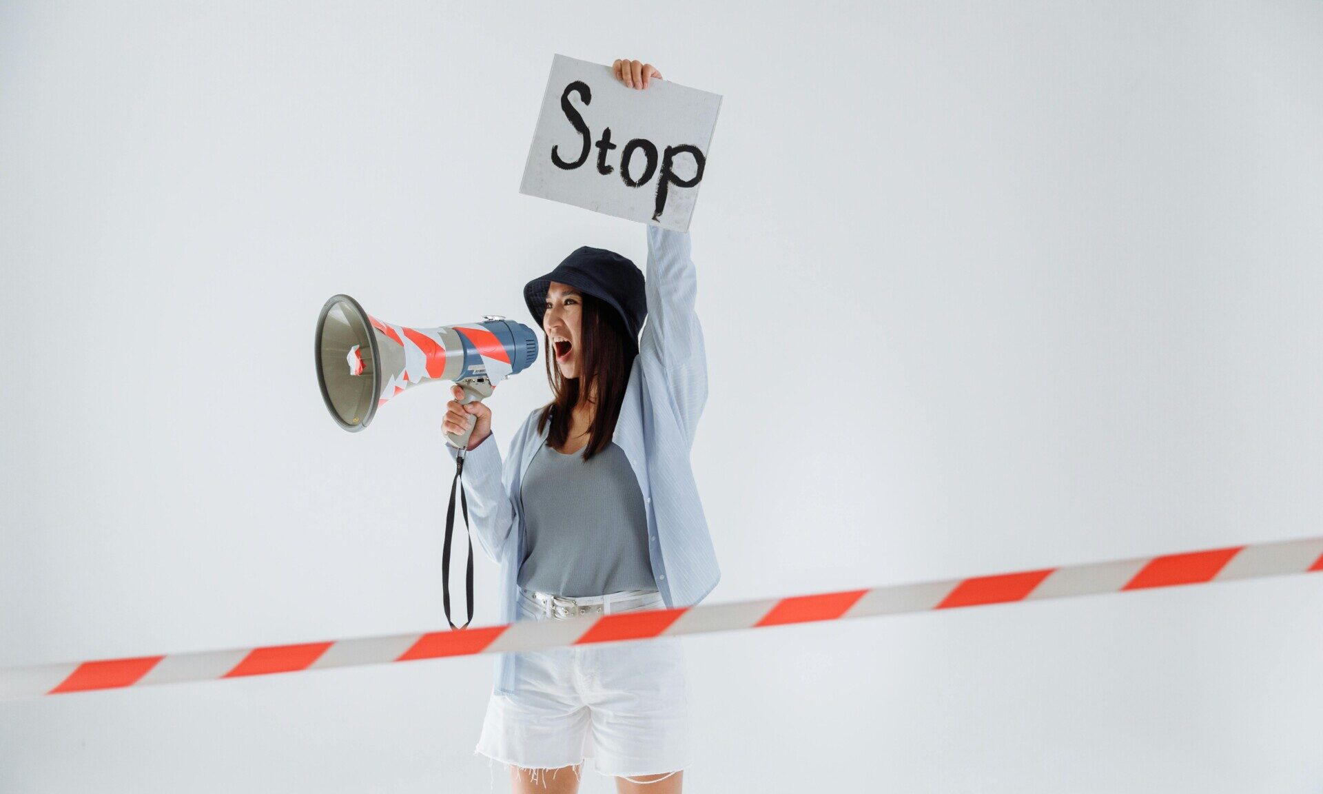 A woman with a megaphone holds a Stop sign, expressing energy and enthusiasm for Salsa and Bachata dance.